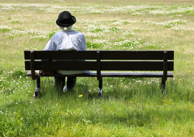 公園のベンチにひとりで座っている高齢女性