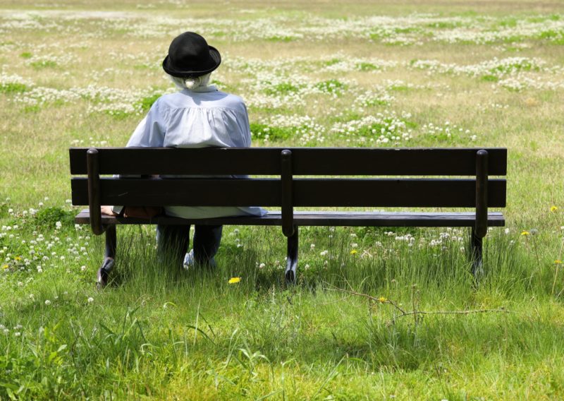 公園のベンチにひとりで座っている高齢女性